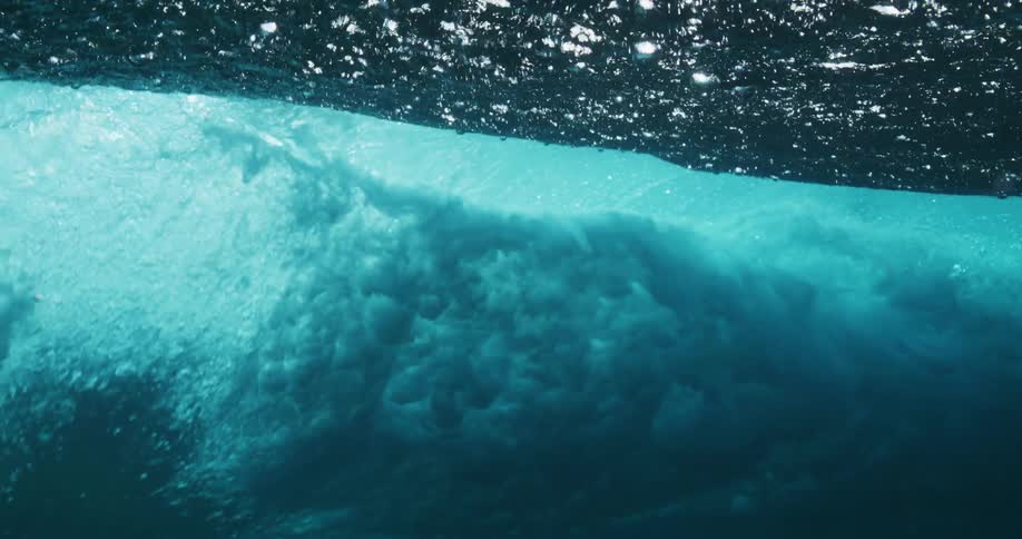 Underwater footage of waves rolling oververhead on the blue ocean waters