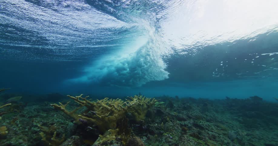 Waves crashing underwater above coral reefs in ocean floor