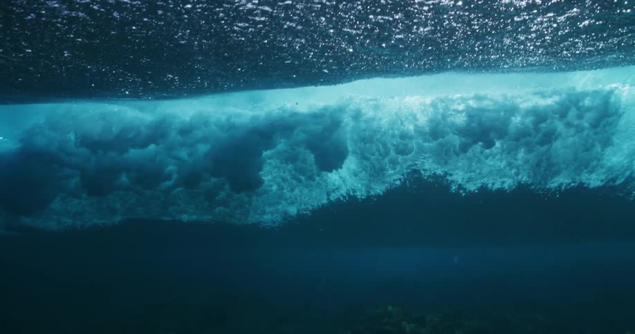 Water ripples and waves as sunlight shines underwater and a wave moves overhead