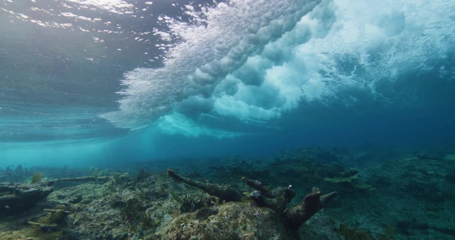 Underwater view of waves crashing above coral reef in the ocean