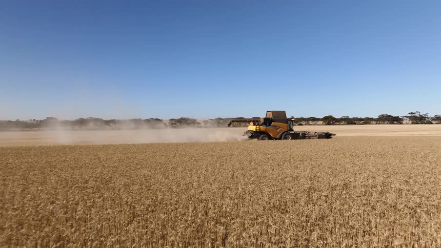 A tractor on a farm is plowing a field and leaving behind a trail of smoke