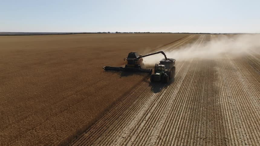 Tractors on a farm are plowing a field and leaving behind a trail of smoke