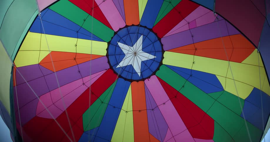 Colorful inflated hot air balloon contrasts with blue of sky
