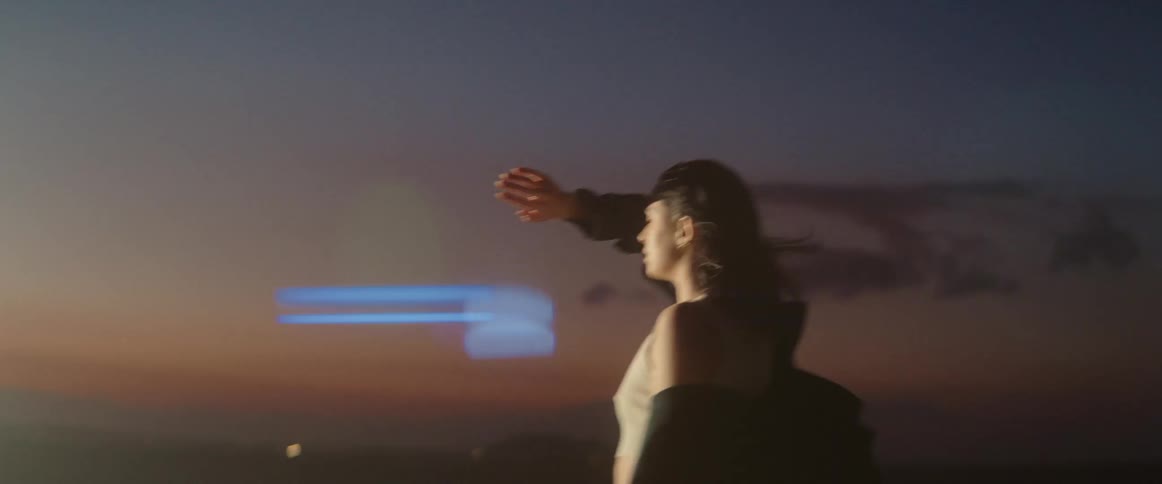 Woman with curly hair black shirt and brown top looks at light in the desert