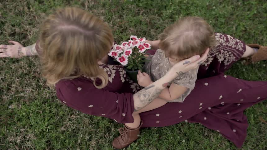 A child is sitting on a woman's lap on a field