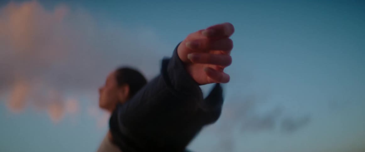 Woman with arms outstretched standing outside on a windy day