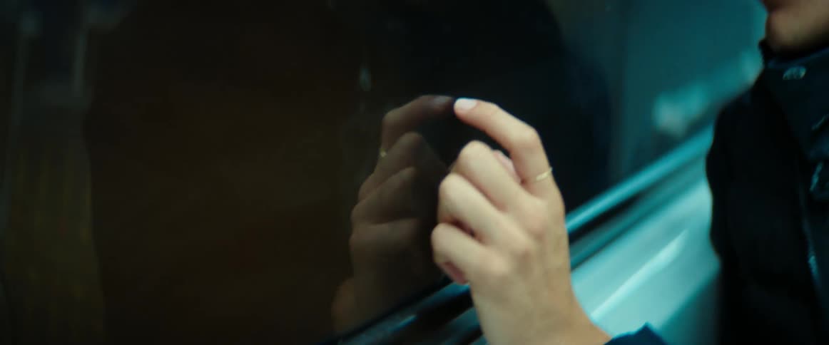 A man tapping his fingers against window glass while looking contemplatively