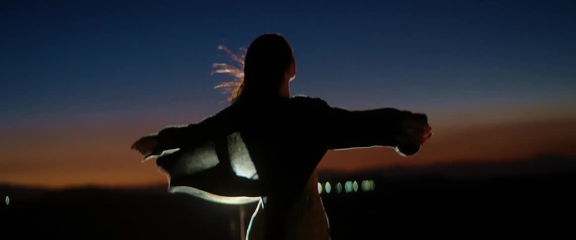 A woman is standing outdoors during the night time