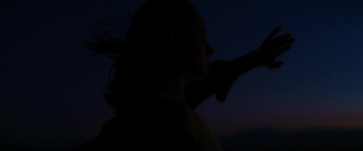 Woman raising her hand as the spotlight shines in the desert