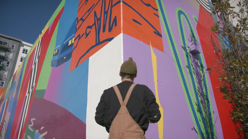 A man painting graffiti on a wall outside
