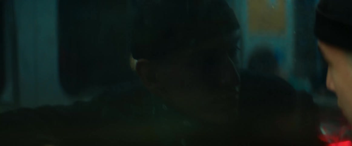 Close up of the face of a man riding a bus at night looking out the window