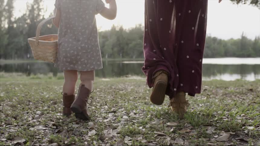 A woman and child walk towards a lake
