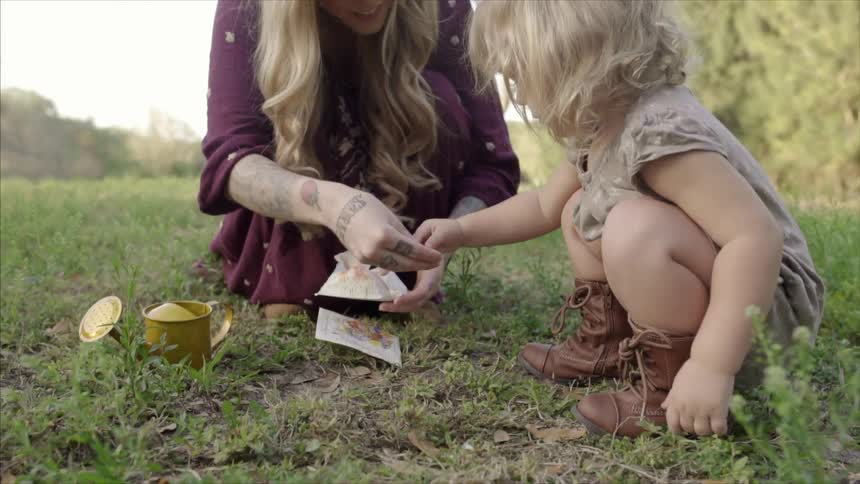 A woman hands some seeds to a child