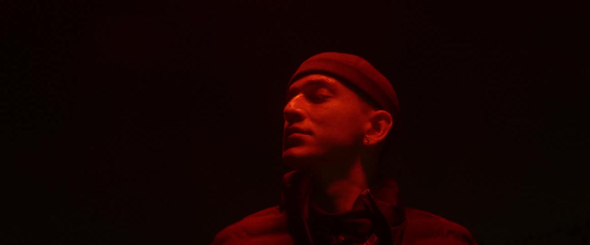Red light shines upon a man standing in the darkness looking around