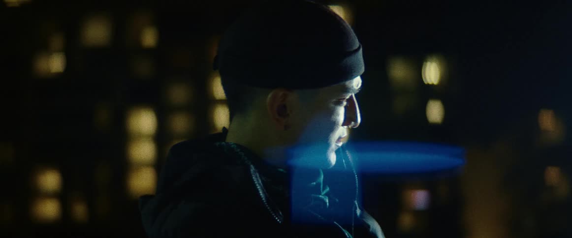 A man stands outside a skyscraper at night