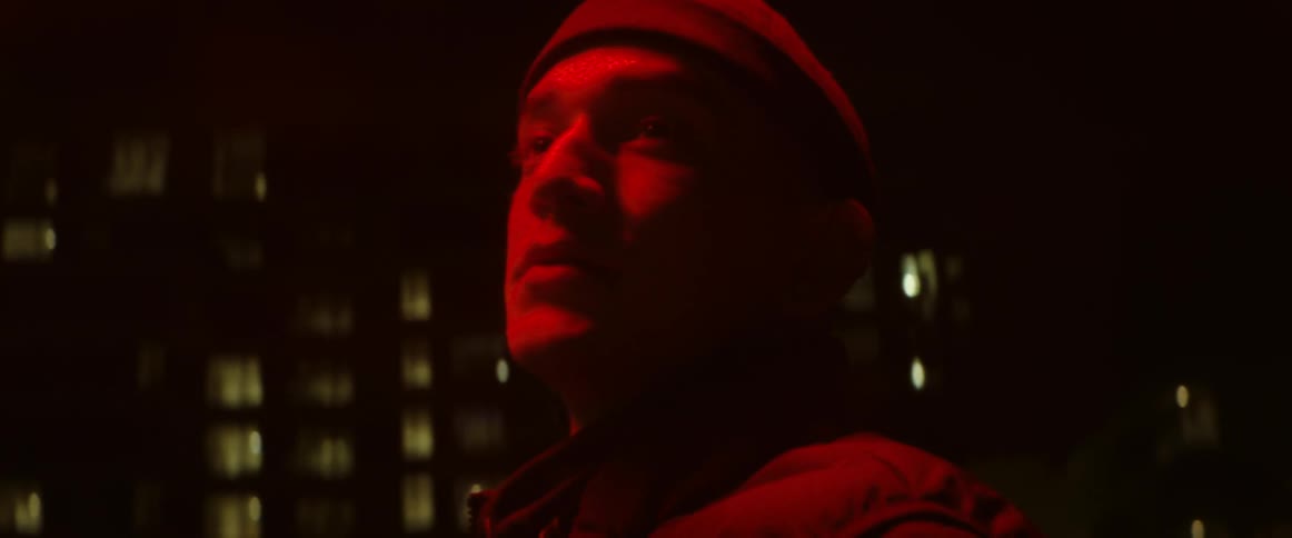 Close up of a man under red lights looking around in the city