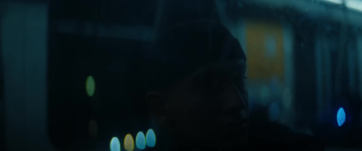 A man sitting on a train looks at his reflection in the window