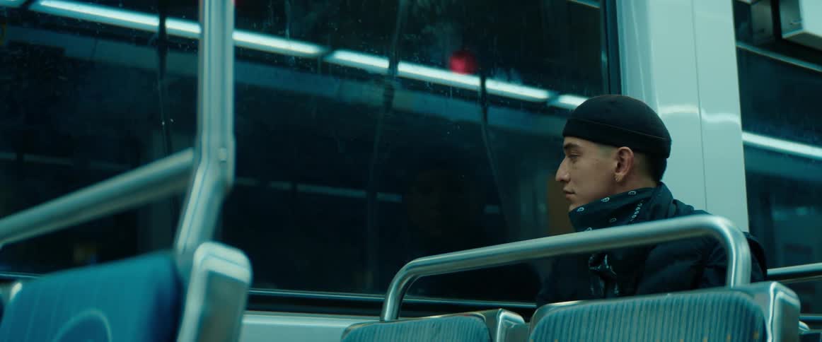A man is sitting on a train looking out the window as it travels at night
