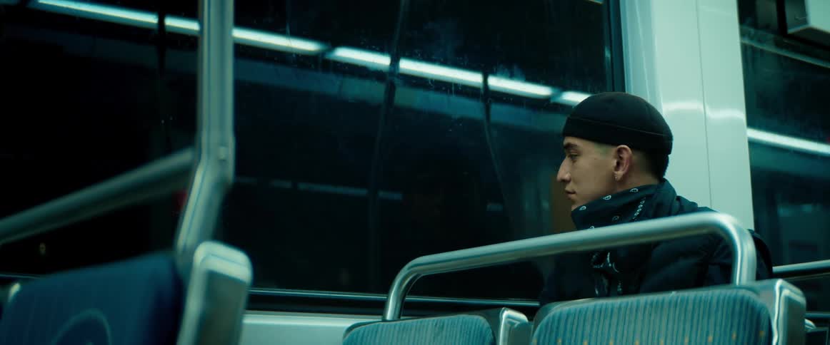 A man is sitting on a train looking out the window as it travels at night