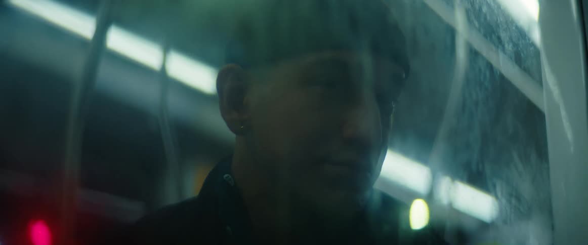 Man wearing black hat sits on subway train looking out window