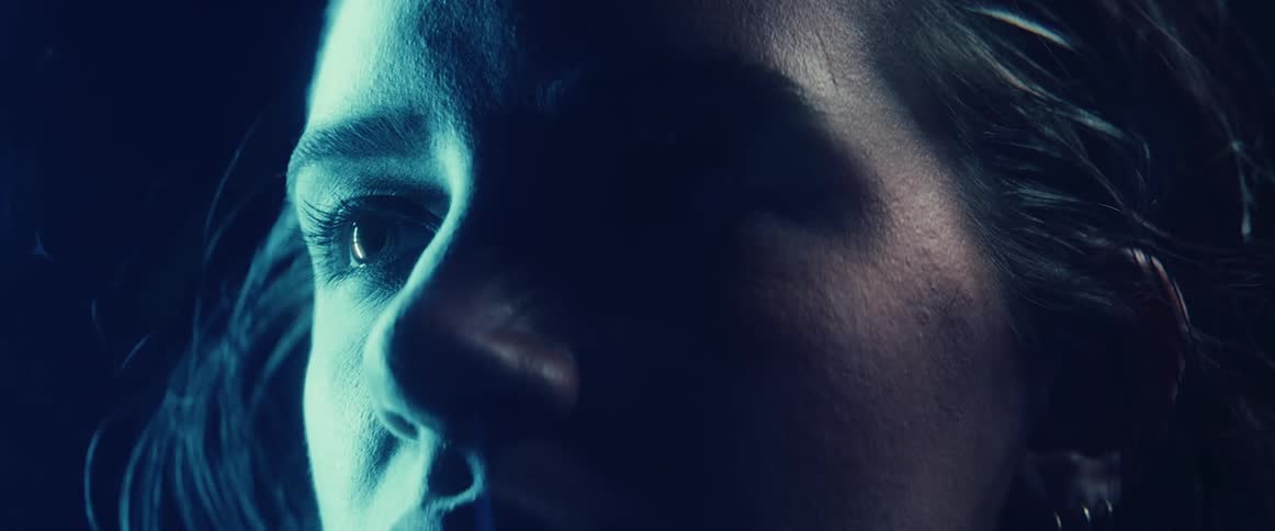A woman blinks while a flashing light illuminates her skin