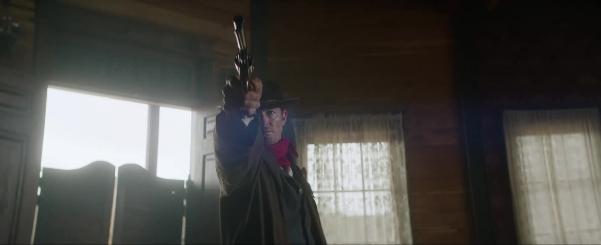 Wild west cowboy points his gun while giving instructions inside a bar