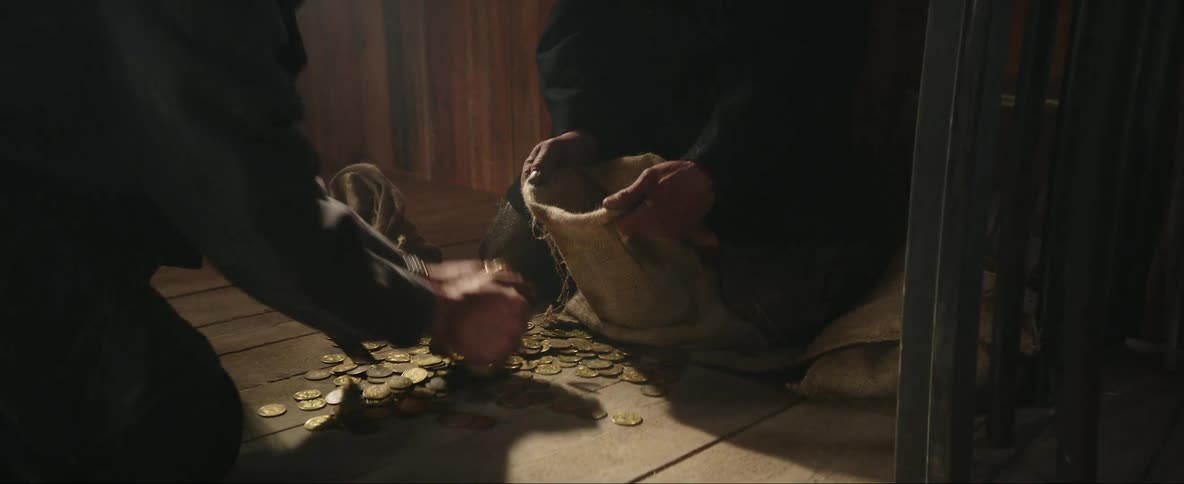 Two cowboys hurriedly stealing gold coins from the floor of a room