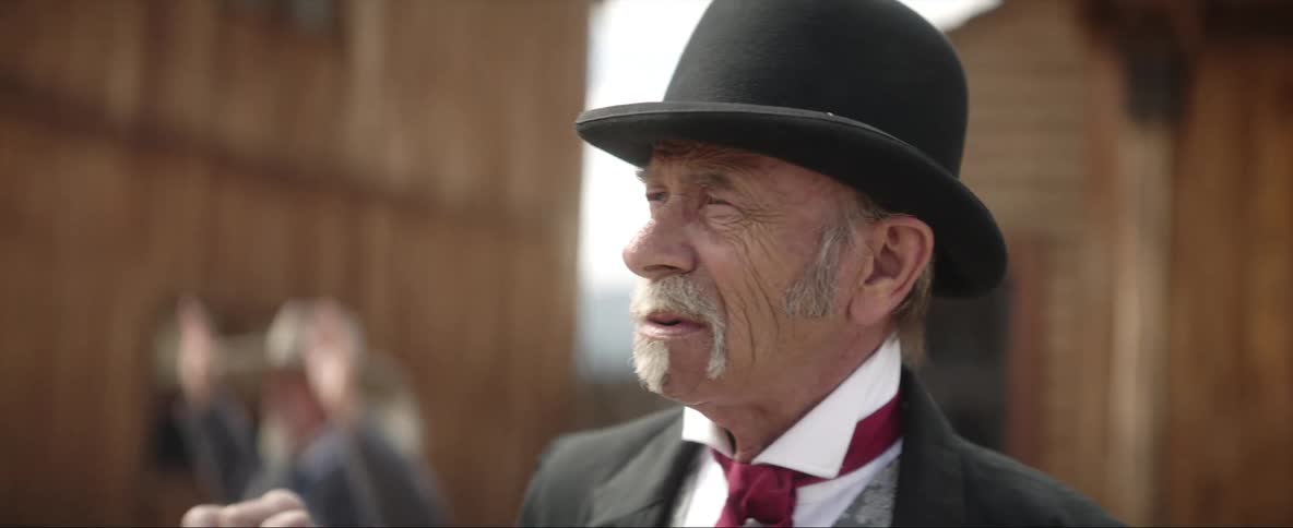 A man is standing outdoors and wearing a hat