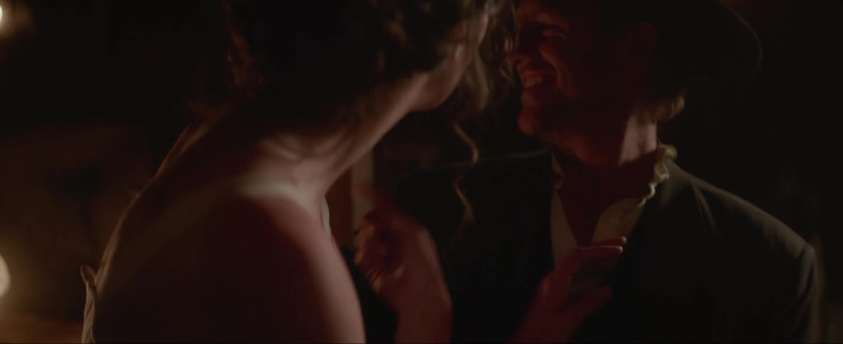 Woman sits in cowboys lap and talks as they both smile