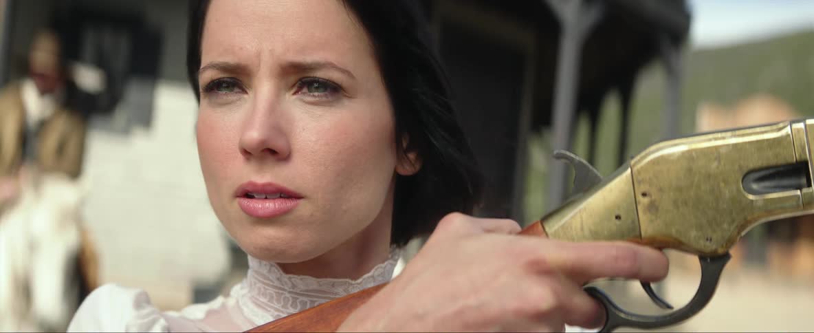 A female holding aiming a rifle in an old western setting