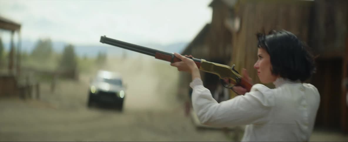 A woman aiming a gun surrounded by men on horses then she starts to shoot