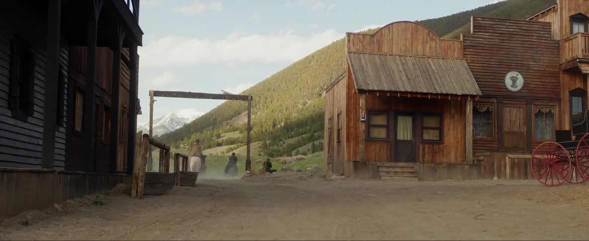 Four men ride out of a small rural town on horses
