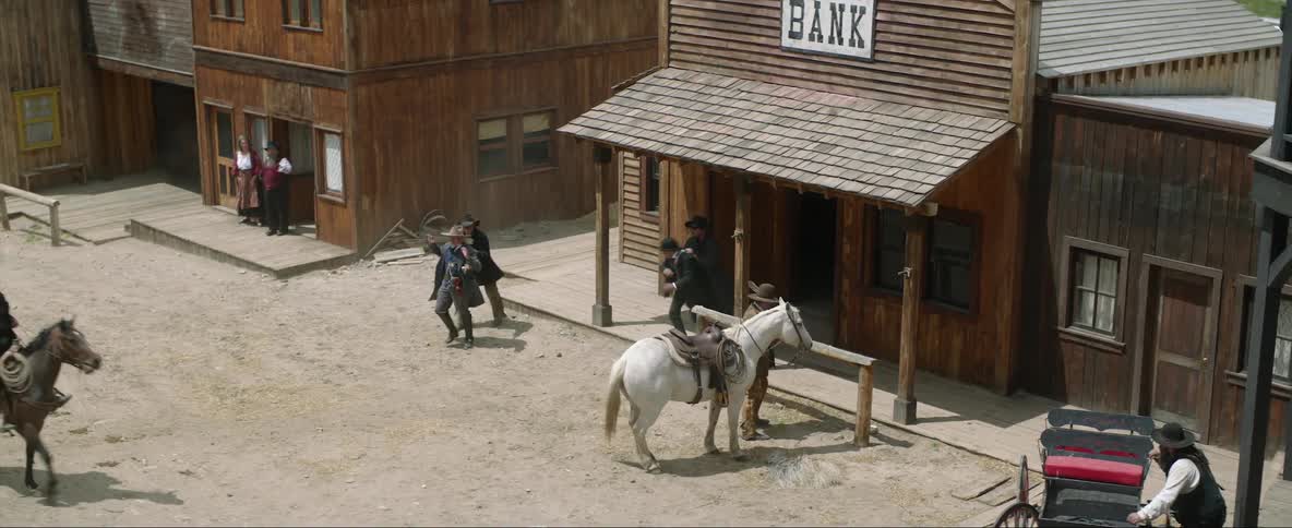 Old west town folk watch as outlaws rob bank holding bank employees at gunpoint