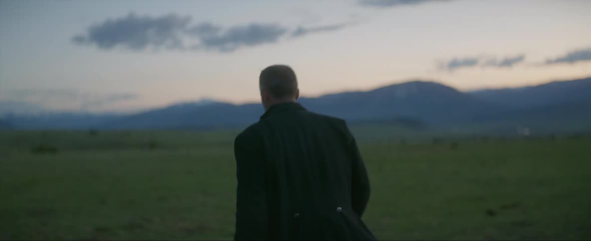A concerned looking man turning and walking away in a rural field