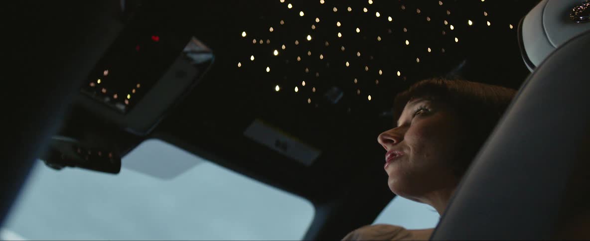 A woman flying a plane looks up at a control lit panel above her