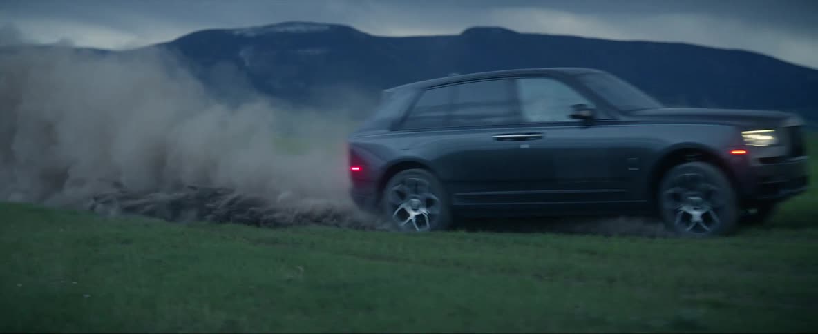 A vehicle sends up a cloud of dust while making drifting turn in a field during the day