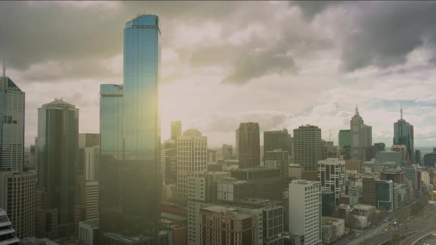 The sun shines behind a city skyline