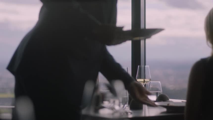 A woman is holding a glass as food is served