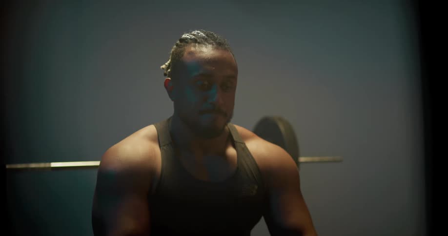 Man sits on weight bench and takes deep breaths while adjusting himself