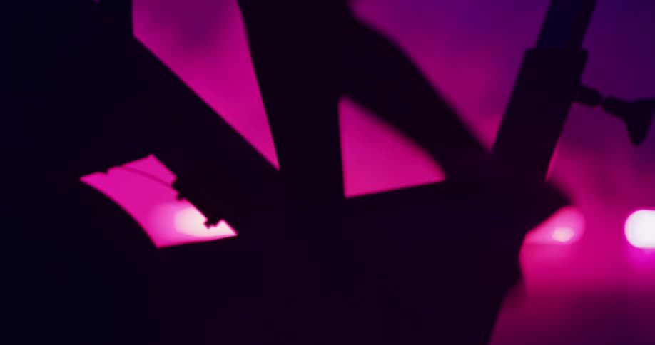 Person exercises on machine silhouetted against colored lighting as smoke spreads in the background