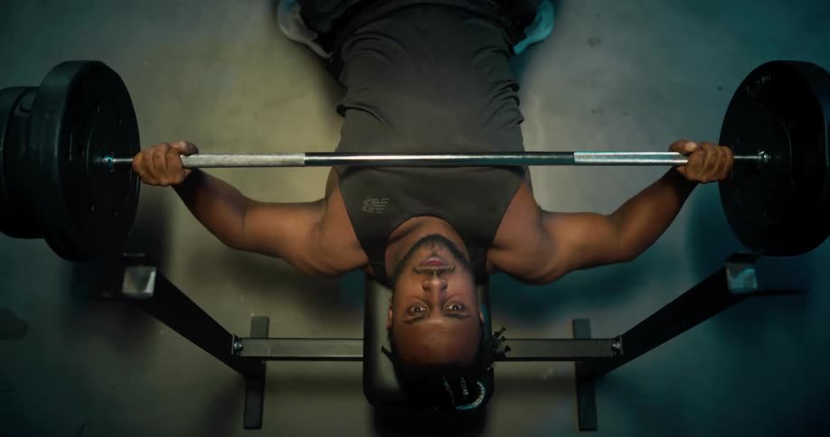 A man lifts weights while lying on a weight bench