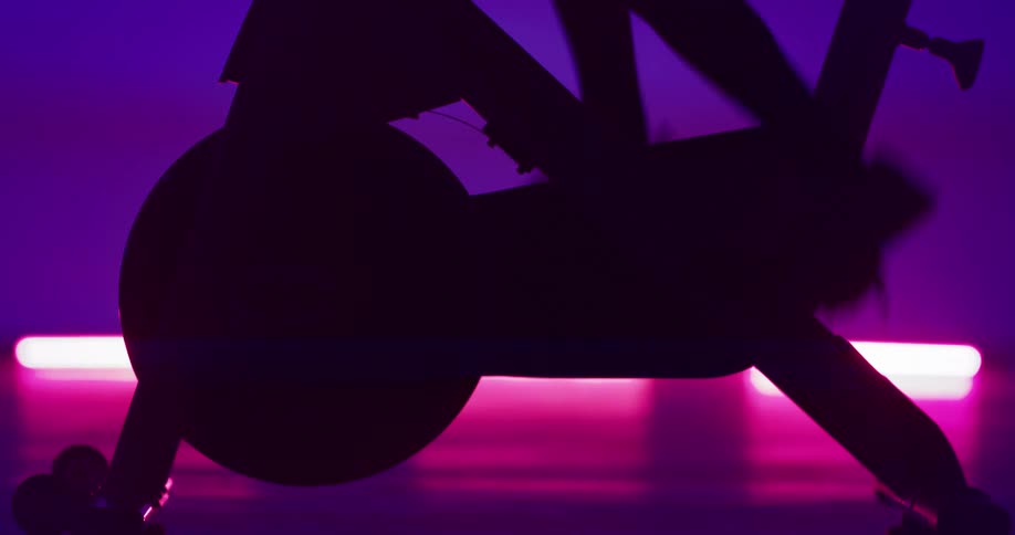 A woman gets on a stationary bike and starts pedaling