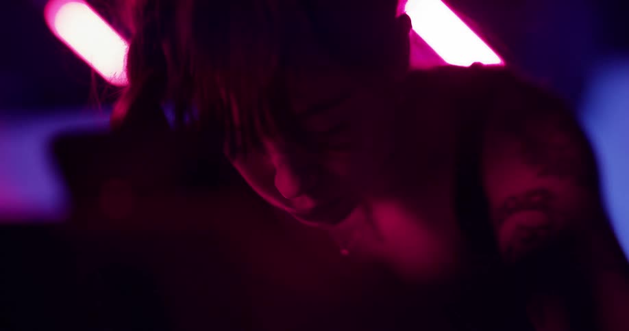 A female exercising on a stationery bike under neon lights