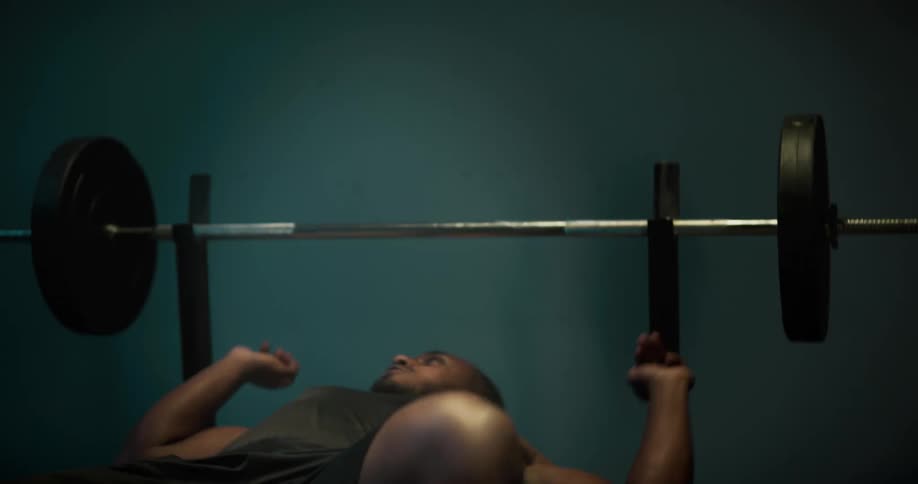 Strong young muscular man covered in sweat lift weights at the gymtion