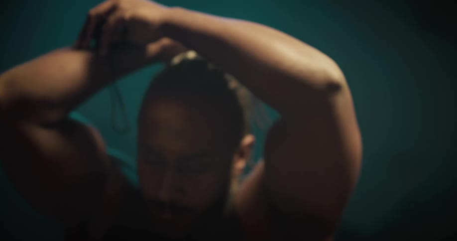 A black male placing his braided hair in a hair tie