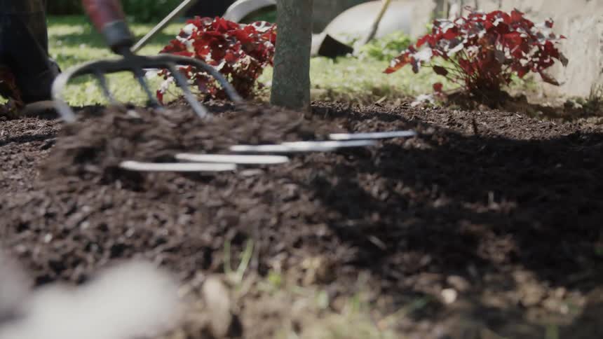 A man spreading compost on a garden
