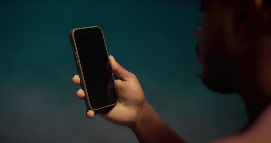 Close up of a man holding a phone with the screen turned off