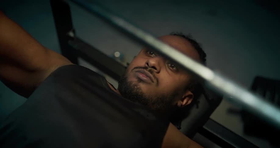 A man lifts weights on a weight bench indoors