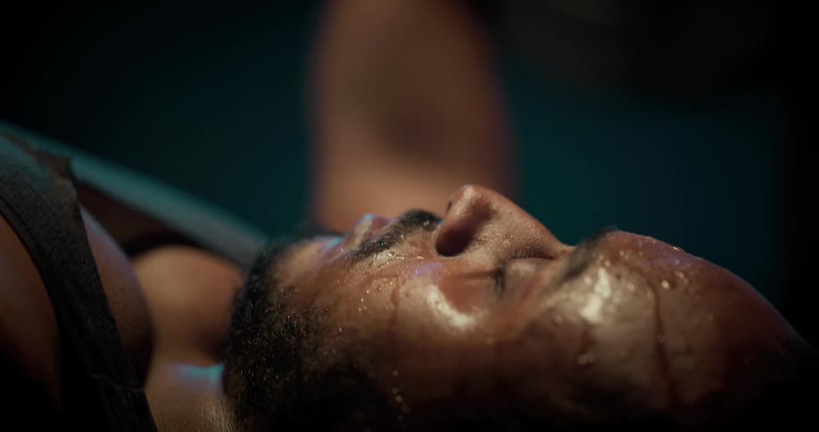 Man sweating heavily performs a barbell bench