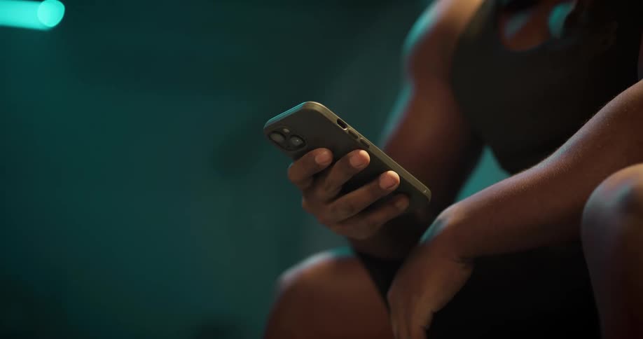 A man is sitting down holding his cell phone